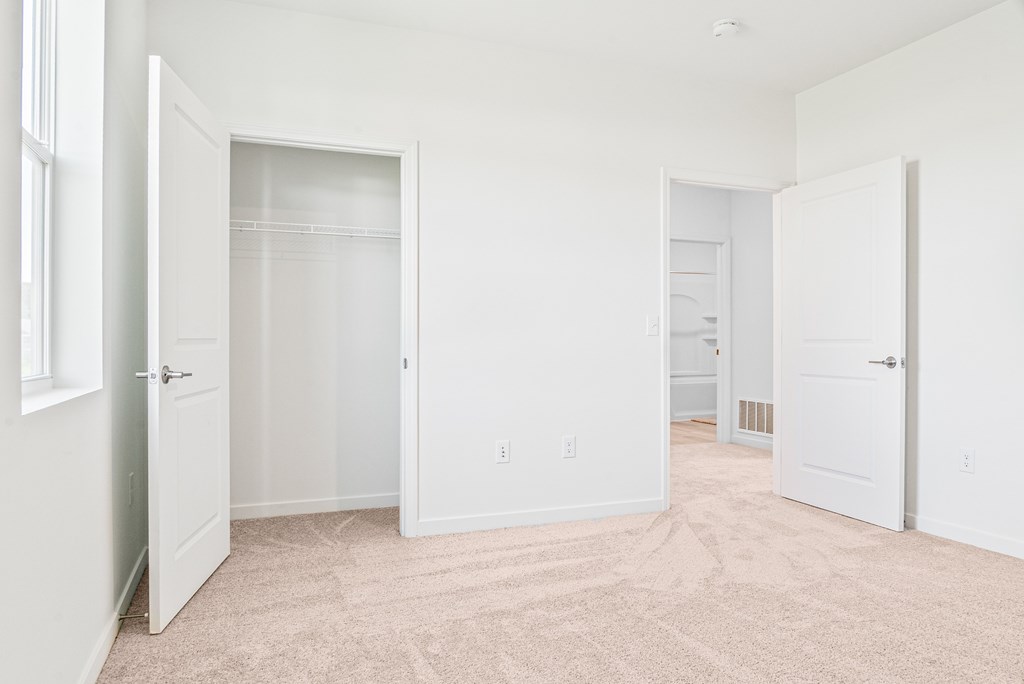 A white room with carpet flooring and three open doors. at Union at Oak Grove, Howell, Michigan