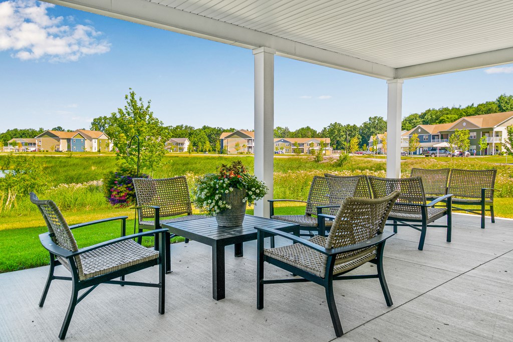 A patio with a table and chairs overlooking a residential area. at Union at Oak Grove, Howell, 48855