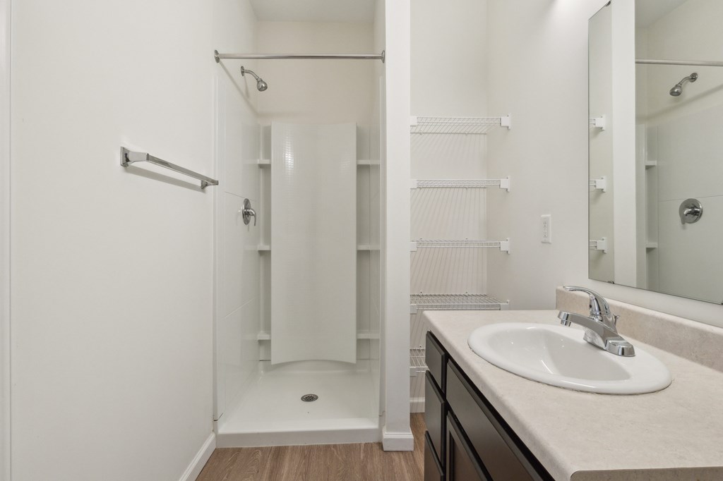 A white bathroom with a sink, mirror, and shower at Union at 16th, Indianapolis, IN