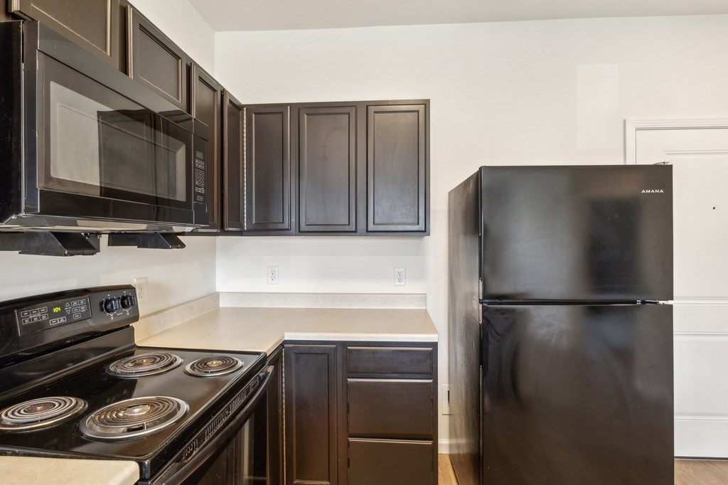 A black stove top oven sits under a black microwave in a kitchen at Union at 16th, Indianapolis, IN