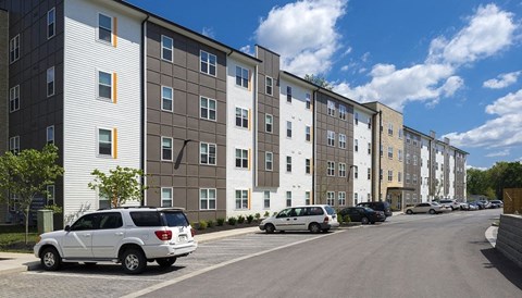 A row of modern apartment buildings with cars parked in front.