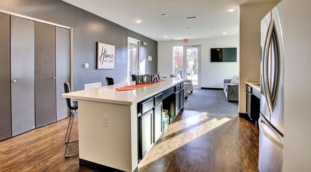 A kitchen with a white counter top and a fridge on the right.at Union at Crescent, Bloomington, 47404  