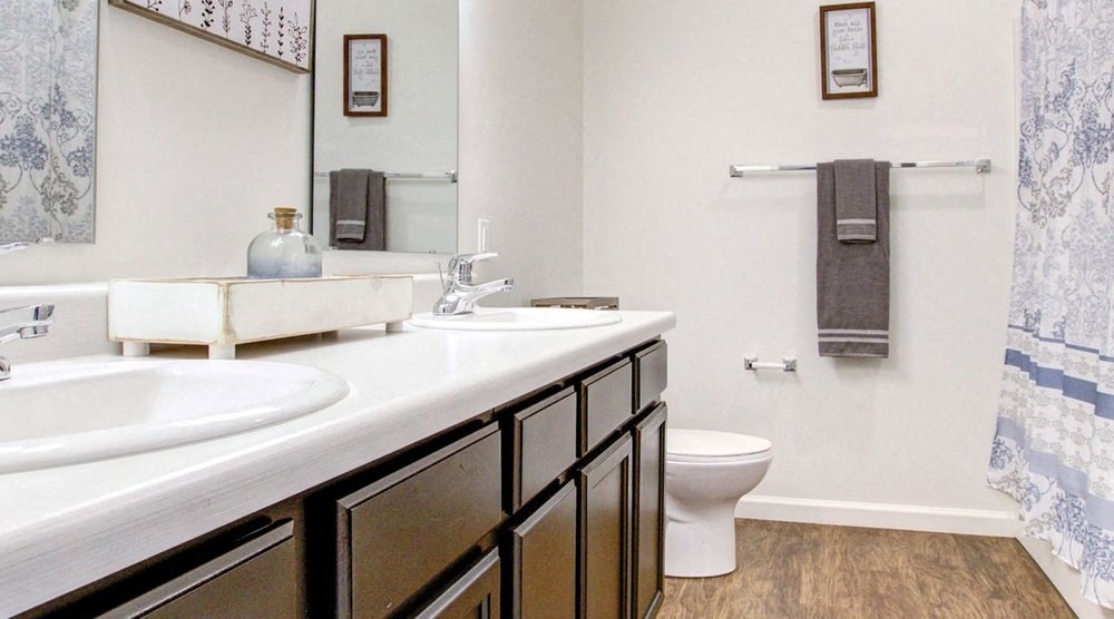 A bathroom with a white sink, black drawers, and a white toilet.at Union at Crescent, Bloomington  