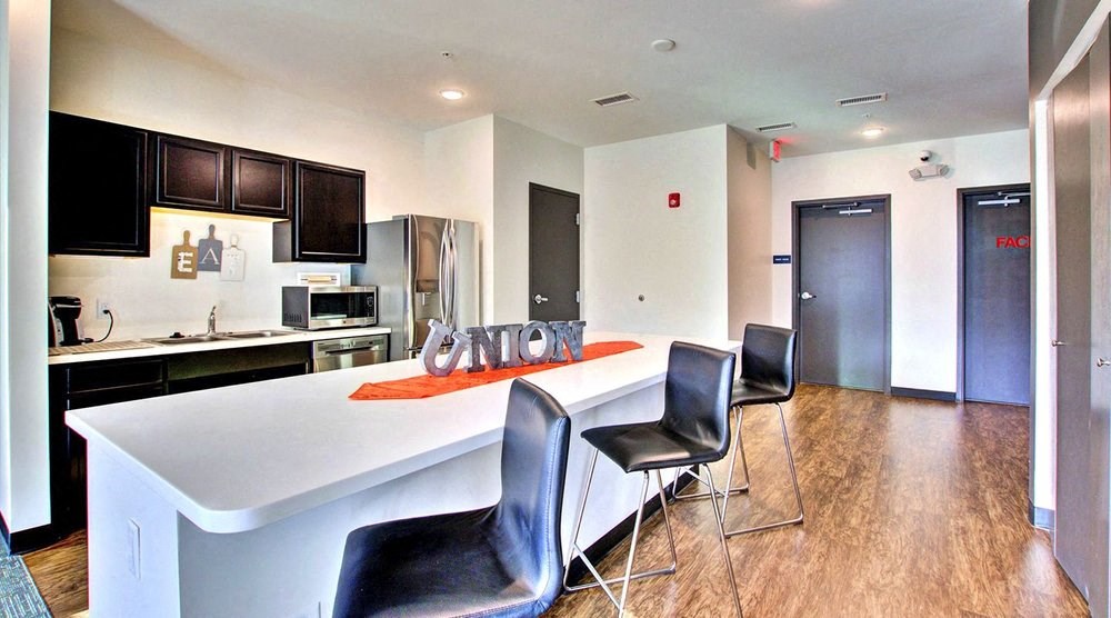 A modern kitchen with a white island and black chairs.at Union at Crescent, Bloomington, IN  