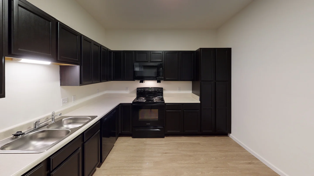 A kitchen with black cabinets and a stove top oven.at Union at 16th, Indiana, 46222