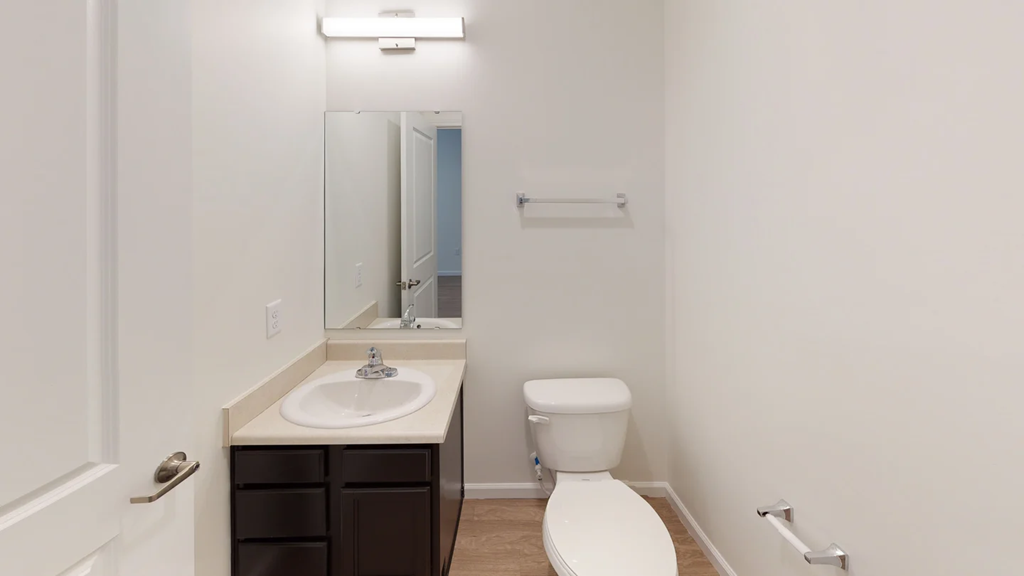 A white toilet sits next to a sink in a small bathroom.at Union at 16th, Indianapolis, IN