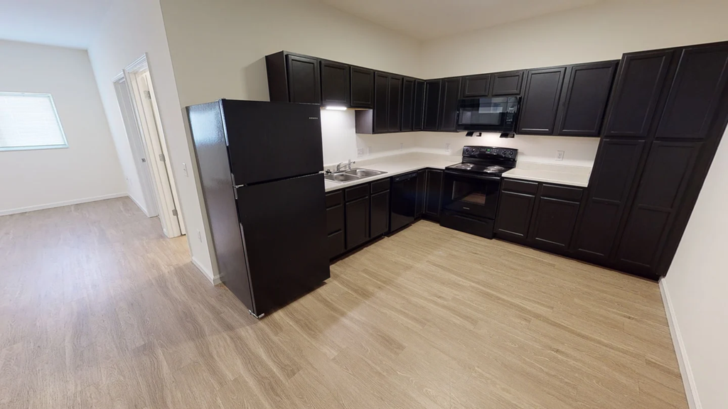 A kitchen with black cabinets and a black fridge.at Union at 16th, Indianapolis, 46222