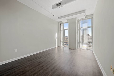 A room with wooden floors and a window with blinds.