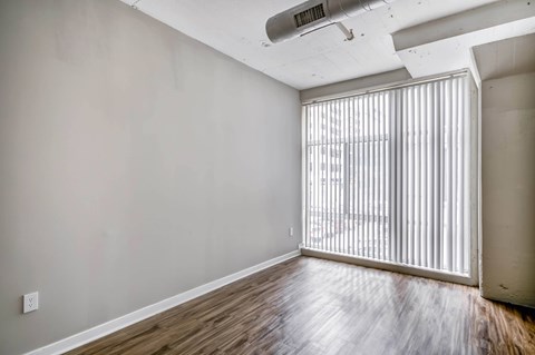 A room with wooden flooring and a window with blinds.