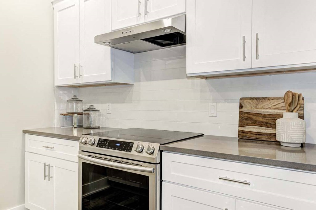 a kitchen with white cabinets and a stove and oven
