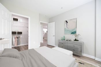 A white couch sits in a bright room with a grey sofa and a white dresser.