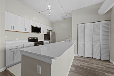 A kitchen with white cabinets and a white island.