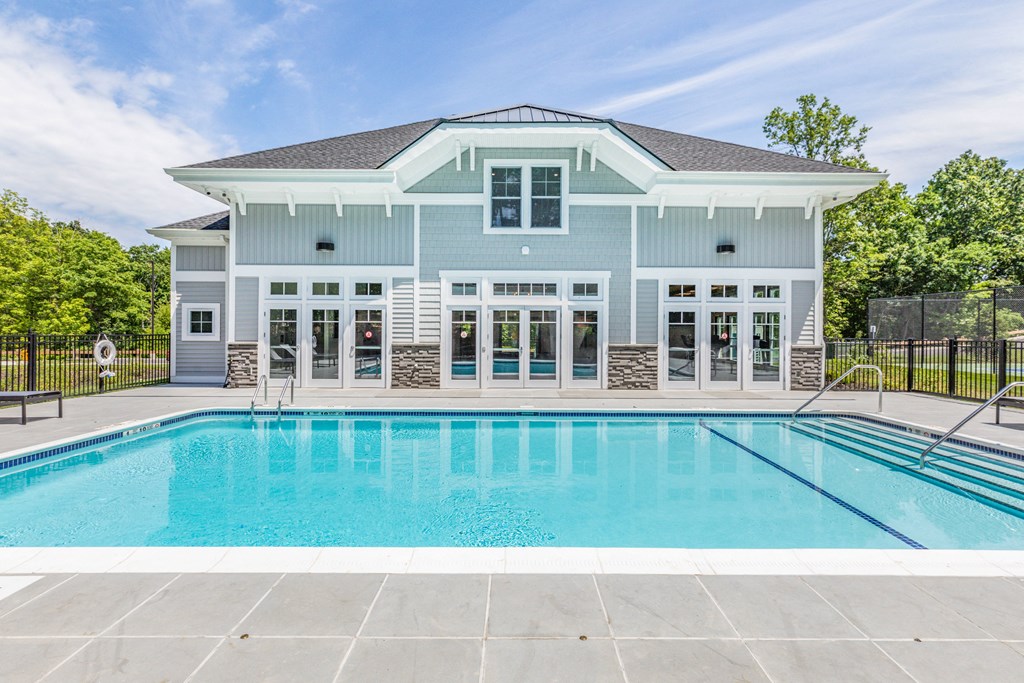 a swimming pool in front of a blue house with a pool