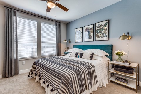 A bedroom with a bed, a nightstand, and a ceiling fan.
