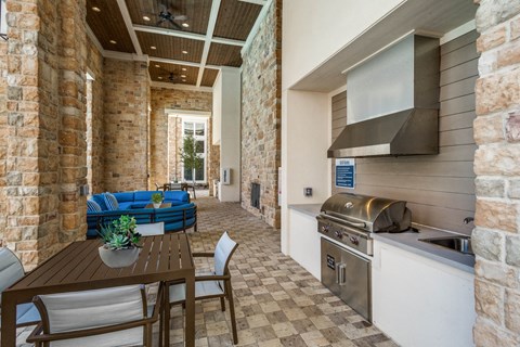 A kitchen with a table and chairs in the foreground and a brick wall in the background.