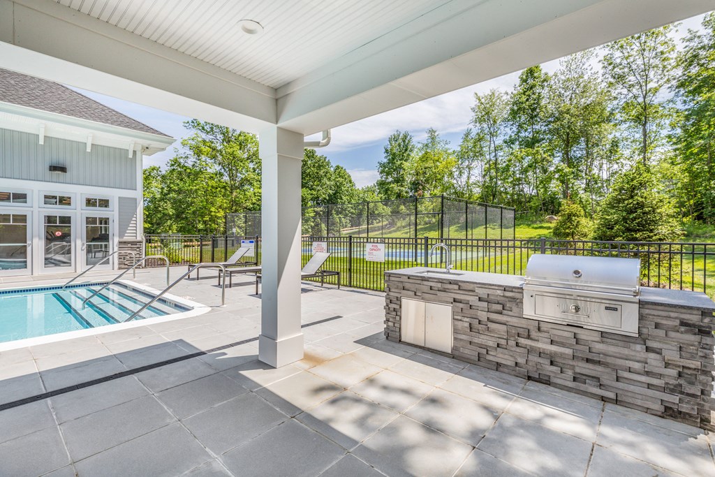 the pool and patio of a house with a grill and a swimming pool