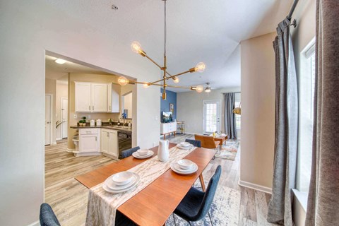 a dining room table with chairs and a kitchen in the background