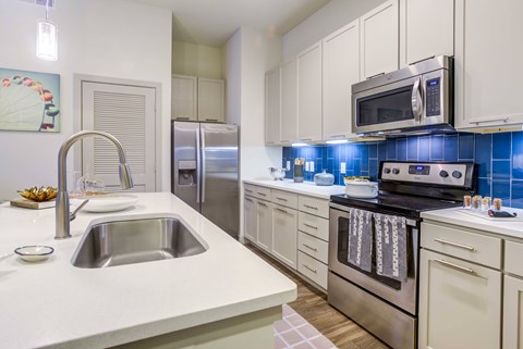 A modern kitchen with a stainless steel oven and white cabinets.