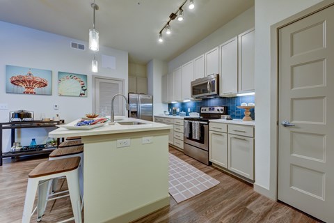 A kitchen with a white counter and cabinets, a sink, and a refrigerator.
