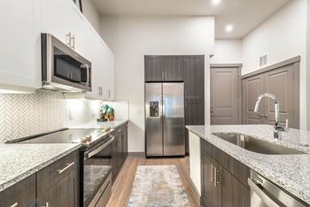A kitchen with a refrigerator, microwave, and sink.t at The Bridge at McKinney, Texas