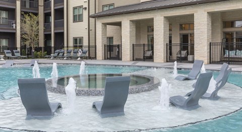 A fountain in the middle of a pool surrounded by chairs.at The Bridge at McKinney, Texas, 75069