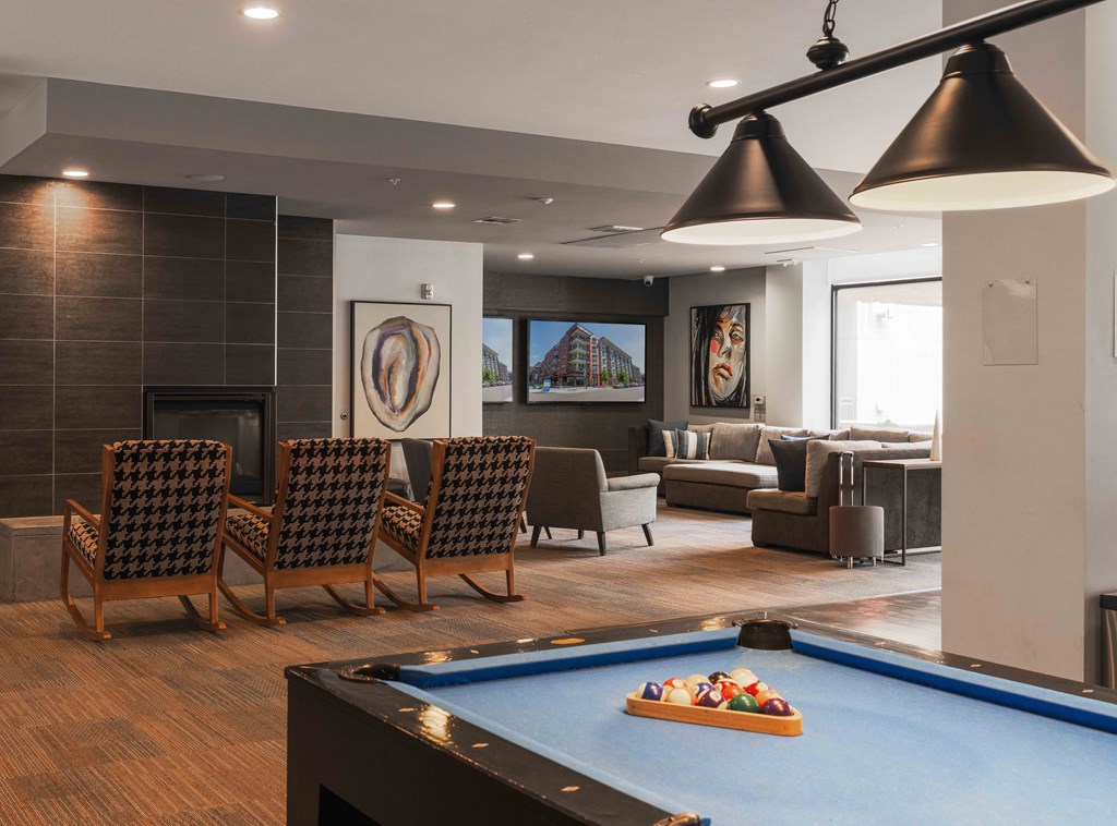 A pool table with a blue cloth and a pool game set up in a room with a fireplace and a couch at Regatta Sloans Lake Apartments, Colorado, 80204