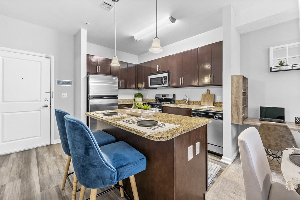 a kitchen with an island with a breakfast bar and two blue chairs  at Harbor Pointe, Bayonne, NJ