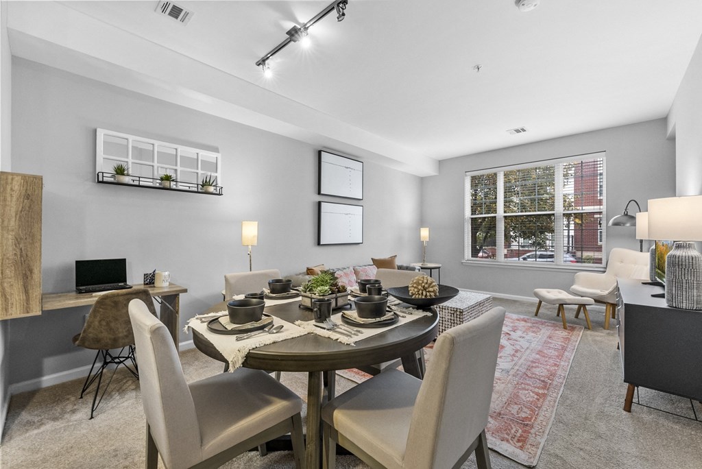 a living room with a large window and a dining room table with chairs  at Harbor Pointe, Bayonne, NJ