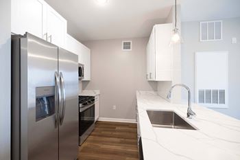 A modern kitchen with a stainless steel refrigerator and a marble countertop. at Harbor Pointe, Bayonne, New Jersey