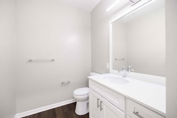 A white bathroom with a toilet, sink, and mirror. at Harbor Pointe, New Jersey