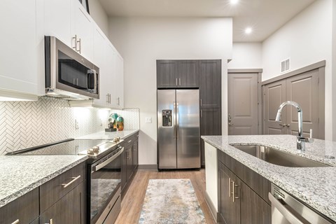 A kitchen with a refrigerator, microwave, and sink.at The Bridge at McKinney, McKinney