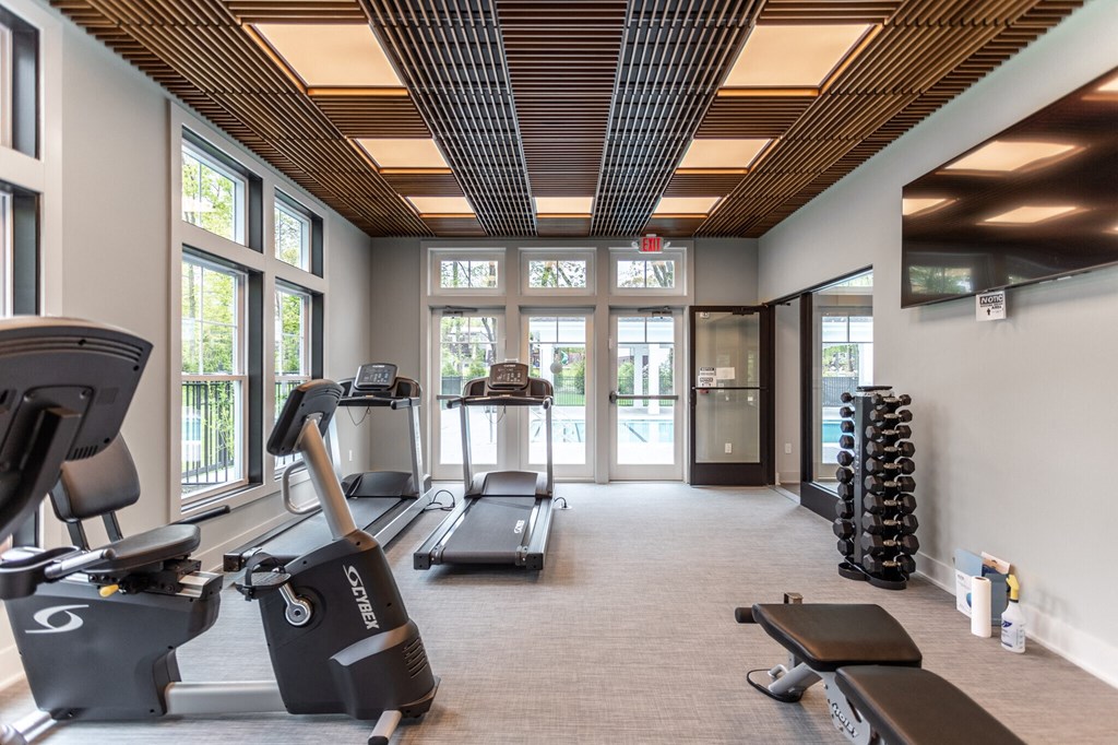 a gym with cardio equipment and windows in a building