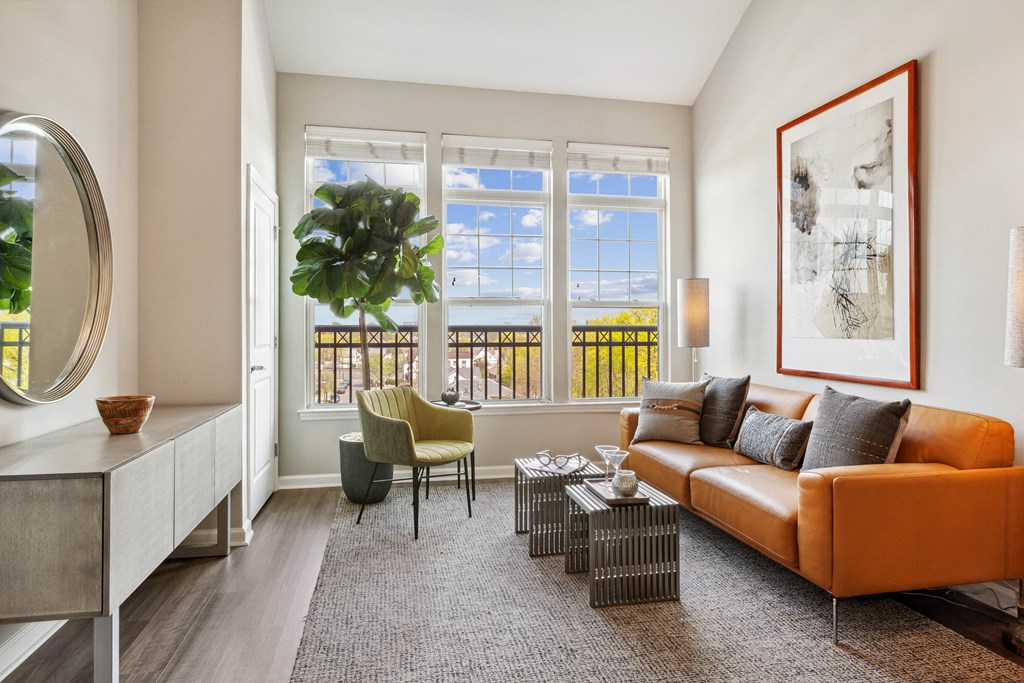 a living room with a brown couch and a large plant in front of a window at Metro 303, New York, 11550