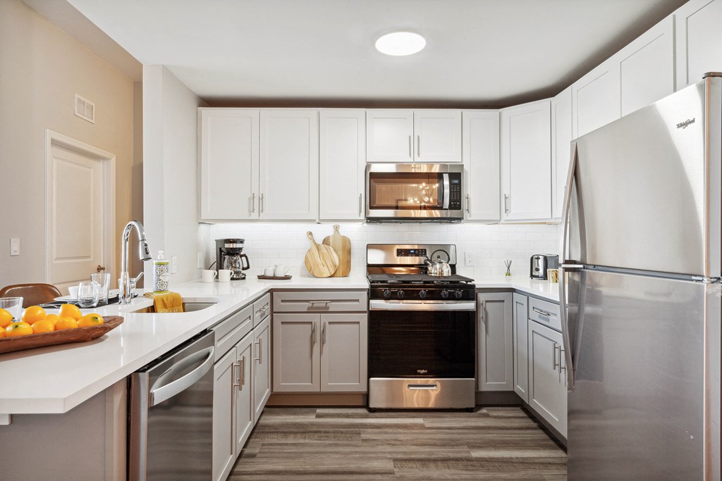 a kitchen with white cabinets and stainless steel appliances at Metro 303, Hempstead