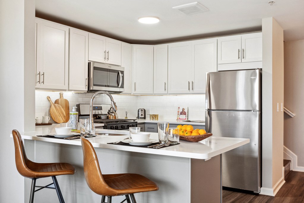 a kitchen with white cabinets and stainless steel appliances at Metro 303, Hempstead, NY