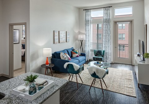 A living room with a blue couch, a chair, and a table with a plant on it.