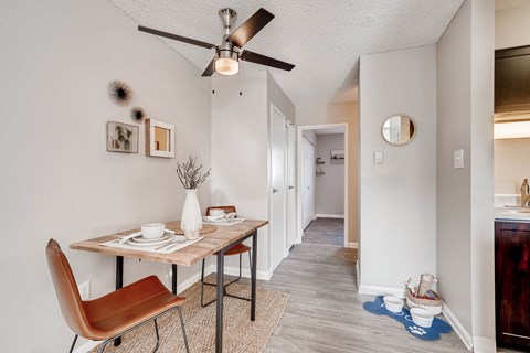 A dining room with a brown chair and a table with a vase of flowers on it at Mountain Vista Apartments, Lakewood