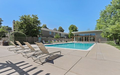 A pool with chairs around it and a building in the background at The Ranch at Bear Creek Apartments, Colorado, 80227
