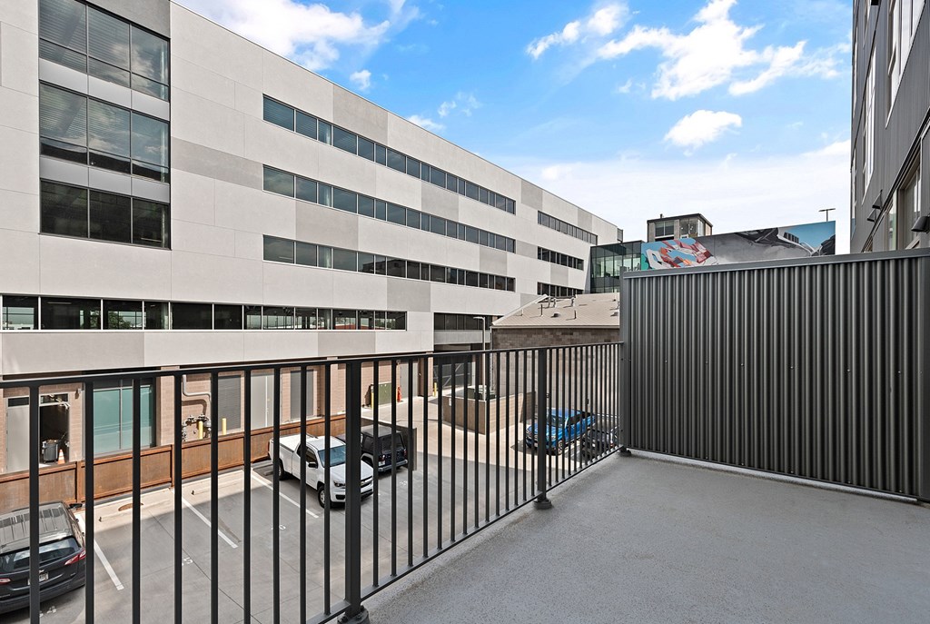 A black metal fence surrounds a parking lot at RiDE at RiNo Apartments, Denver, CO, 80216