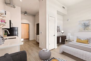 A modern bedroom with a large bed and a kitchen area. at RiDE at RiNo Apartments, Denver 80216