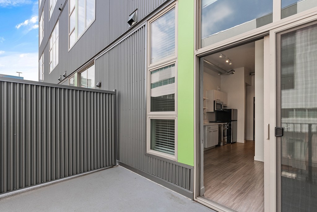 A modern house with a grey exterior and a glass door leading to the interior at RiDE at RiNo Apartments, Denver 80216