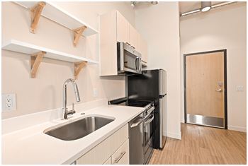A kitchen with a sink, stove, and microwave. at RiDE at RiNo Apartments, Denver