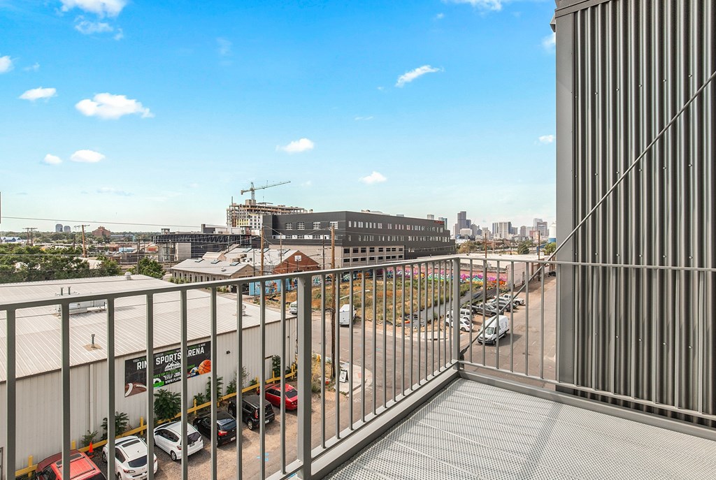 A view from a balcony overlooking a parking lot and buildings at RiDE at RiNo Apartments, Colorado