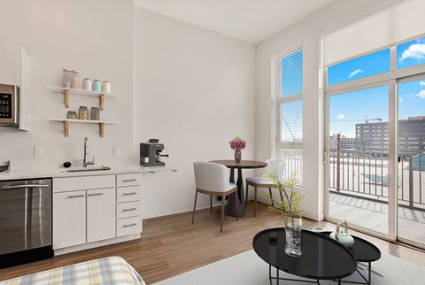 A kitchen with white cabinets and a black countertop with a coffee maker and a microwave.