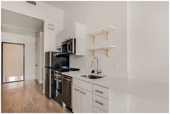 A kitchen with white cabinets and a black stove top oven. at RiDE at RiNo Apartments, Denver