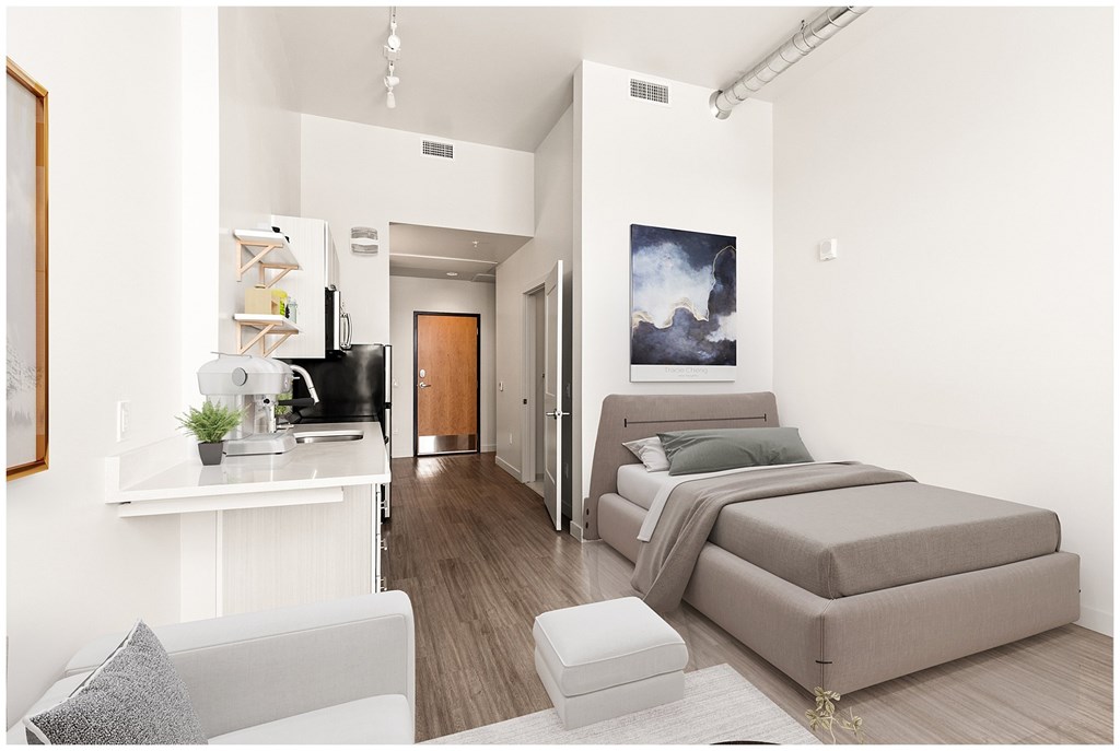 A modern bedroom with a large bed and a kitchen area at RiDE at RiNo Apartments, Denver, Colorado