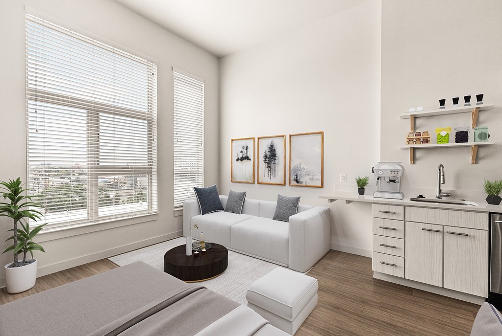A modern living room with a white sofa, a coffee table, and a kitchen area in the background at RiDE at RiNo Apartments, Denver, CO