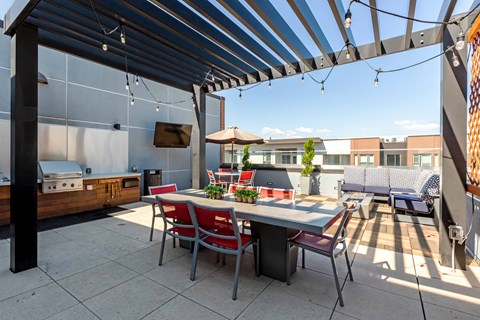 A patio with a table and chairs under a striped awning at Regatta Sloans Lake Apartments, Denver, Colorado