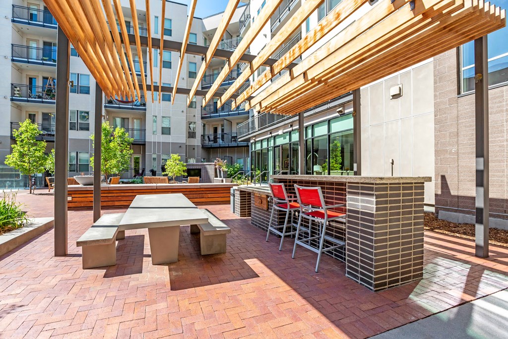 A patio with a table and chairs under a wooden canopy at Regatta Sloans Lake Apartments, Denver, CO