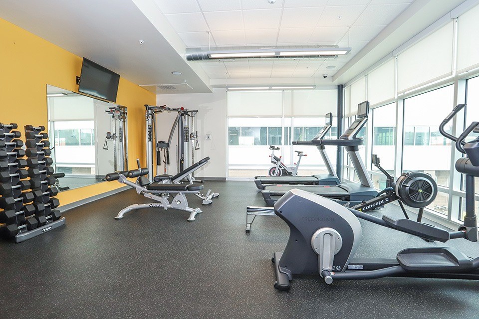 A gym with a variety of equipment including treadmills, weights, and exercise machines at RiDE at RiNo Apartments, Colorado, 80216